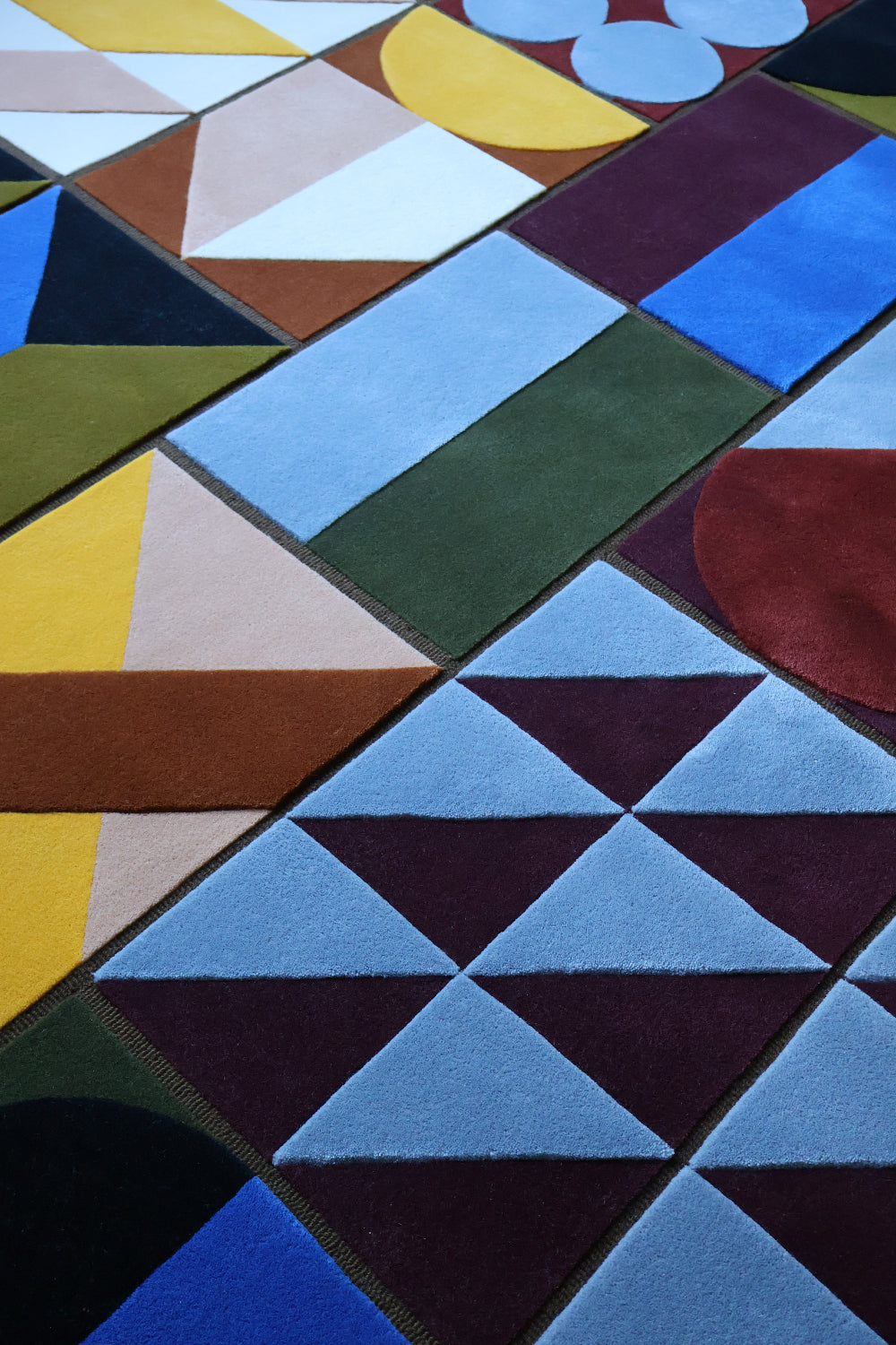 Geometric pattern with triangles and squares in various colors on a textured rug.