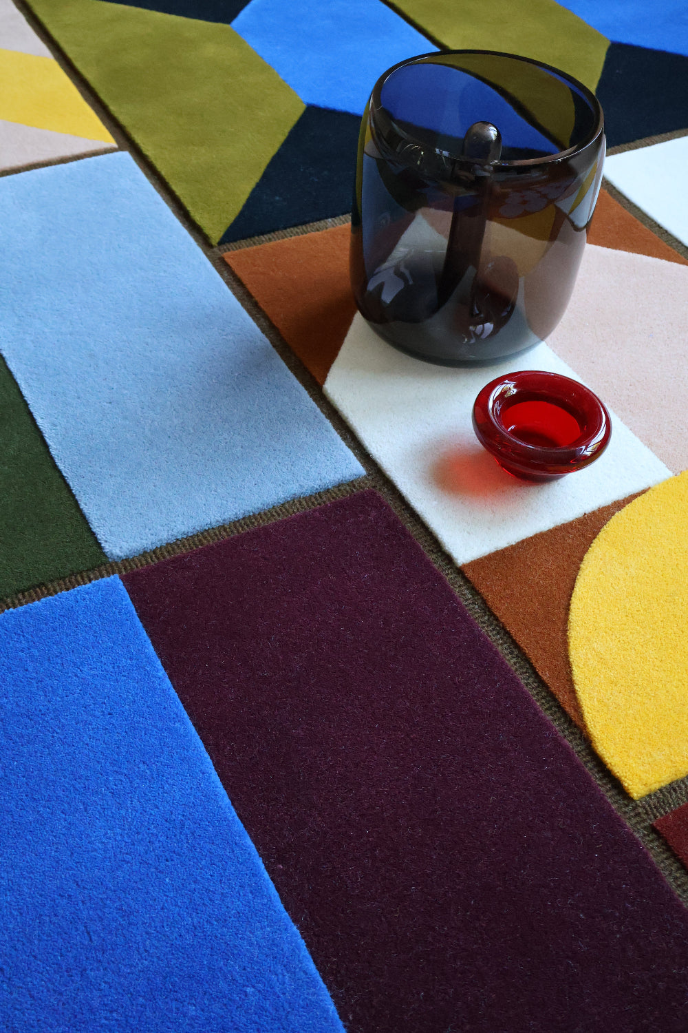 Colorful geometric-patterned rug with a mirror and red object on top