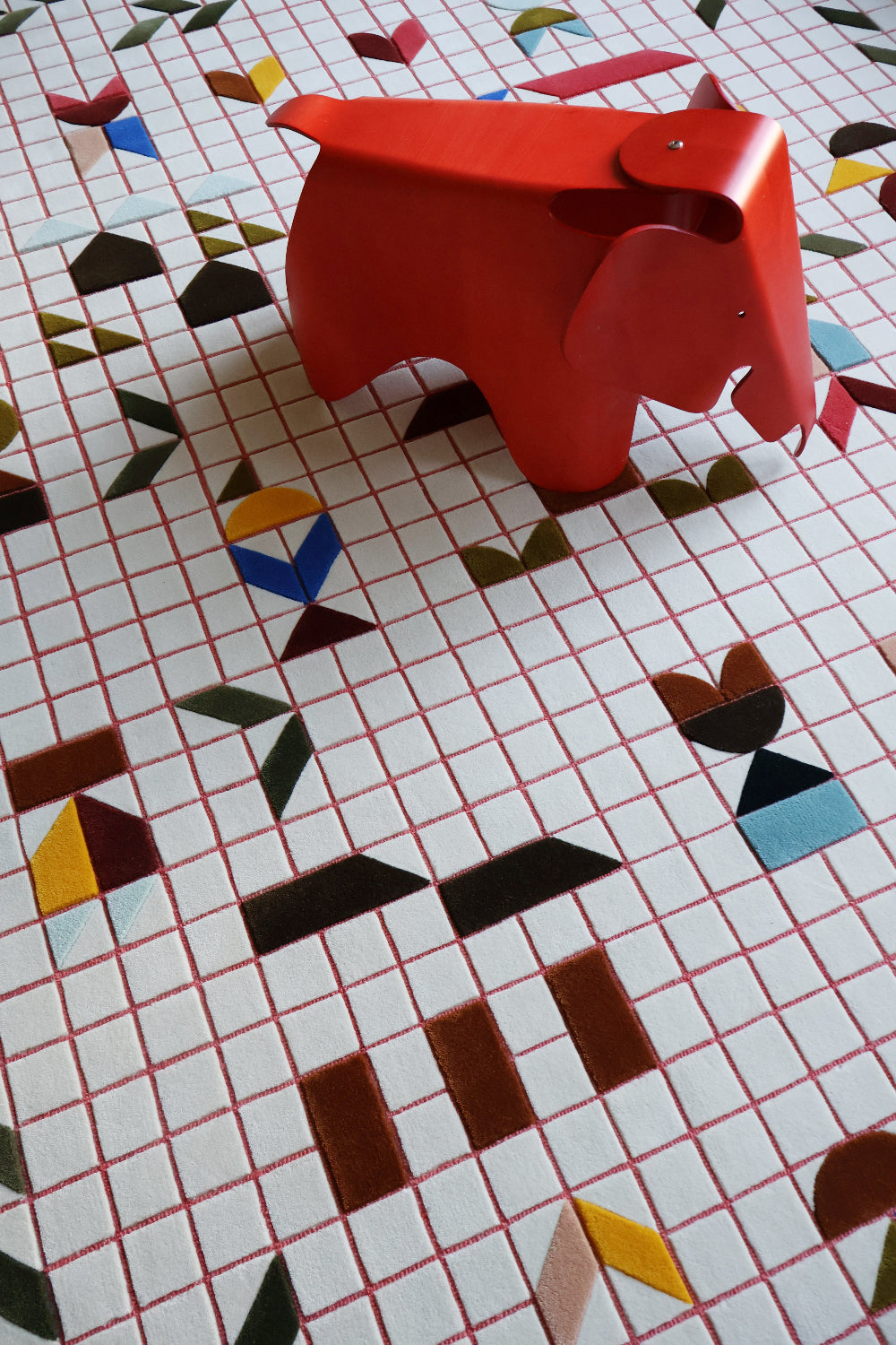 Red elephant-shaped stool on a colorful geometric-patterned floor
