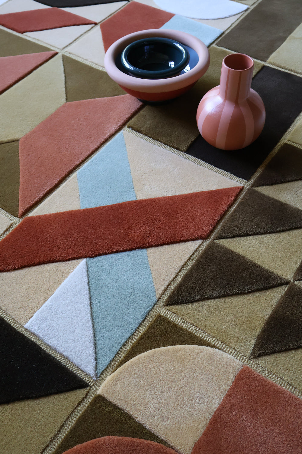 Geometric patterned rug with two pink vases on top