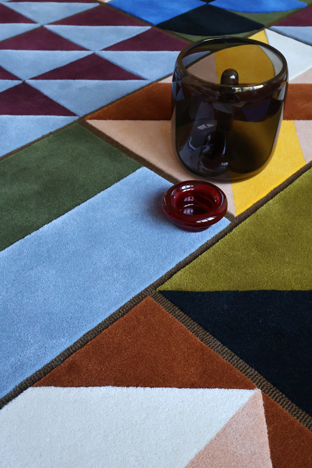 Red wireless earbuds on a colorful geometric-patterned surface