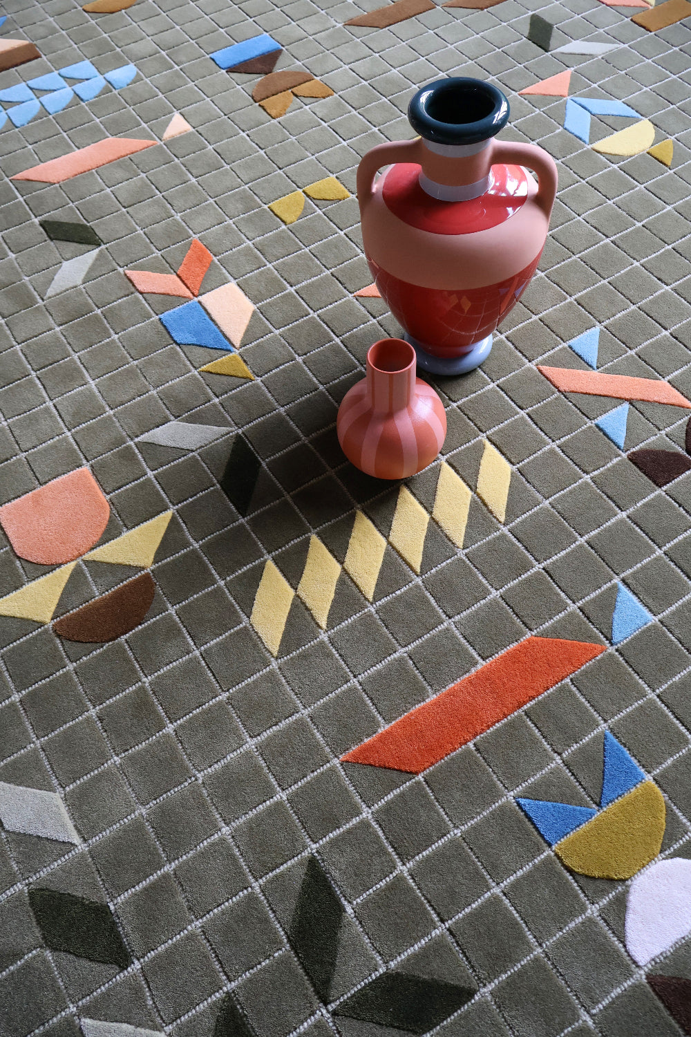 Two pink vases on a gray textured surface with geometric multicolor shapes.