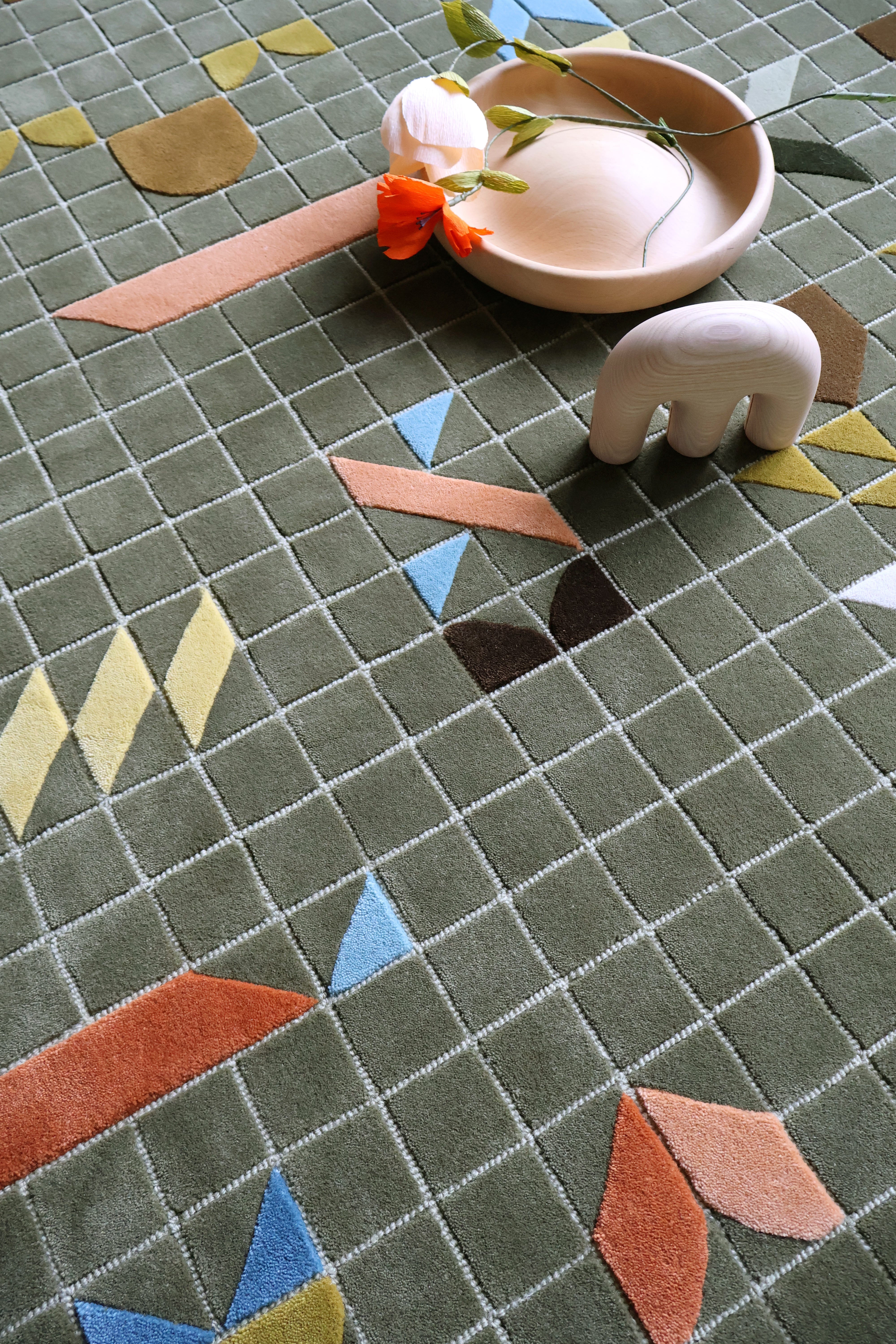 Geometric patterned rug with colorful shapes and a small decorative item on top.